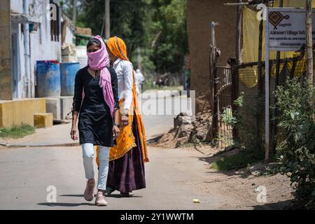 Abhaneri Village, India - 13 aprile 2023. Due donne che indossano abiti colorati camminano lungo una strada nel villaggio di Abhaneri in India Foto Stock