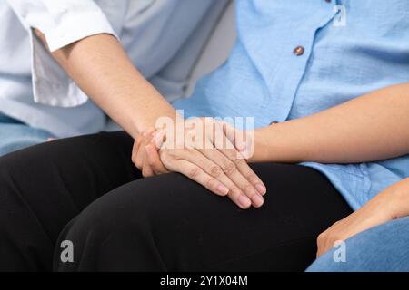 Un medico tiene la mano del paziente, offrendo conforto e incoraggiamento, il loro gesto pieno di compassione e sostegno. Foto Stock