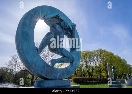 Oslo, Norvegia - 3 maggio 2024: Un'impressionante scultura in bronzo di un uomo che si stacca da una forma circolare domina il paesaggio del Parco delle sculture di Vigeland Foto Stock