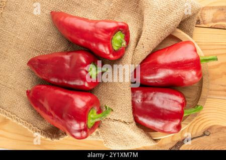 Diversi peperoni rossi dolci con sacchetto di iuta su un tavolo di legno, vista dall'alto. Foto Stock