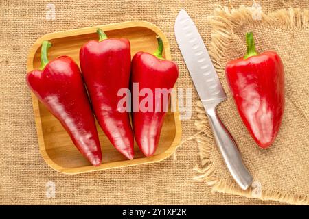 Diversi peperoni rossi dolci con vassoio di bambù su tela di iuta, vista dall'alto. Foto Stock