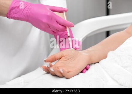 Il cosmetologo fa iniezioni di tossina botulinica sui palmi di una donna contro l'iperidrosi. Cosmetologia femminile, cura della pelle. Foto Stock