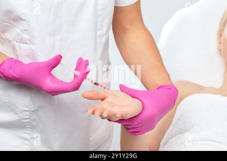 Il cosmetologo fa iniezioni di tossina botulinica sui palmi di una donna contro l'iperidrosi. Cosmetologia femminile, cura della pelle. Foto Stock