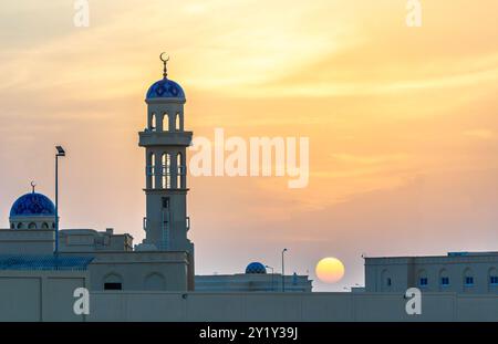 Splendido tramonto sulla moschea con cupole e minareti blu ornati, Ibri, Sultanato dell'Oman Foto Stock