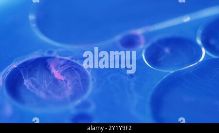 Inchiostro d'olio. Liquido gel. Vernice a bolle. Colore blu-rosa defocalizzato emulsione di bellezza rotante gocce di liquido neon sfocatura dell'acqua sfondo astratto artistico. Foto Stock