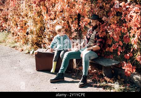 Padre con la valigia e suo figlio. Padre barbuto che dice al figlio di viaggiare. Viaggiatore con molta esperienza. Paternità e educazione. Tempo in famiglia Foto Stock