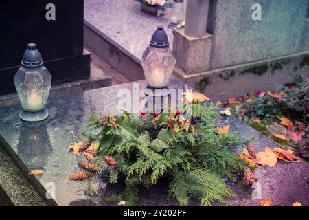 tombe decorate con lanterne, candele accese, fiori colorati di crisantemo, simboli cattolici Foto Stock