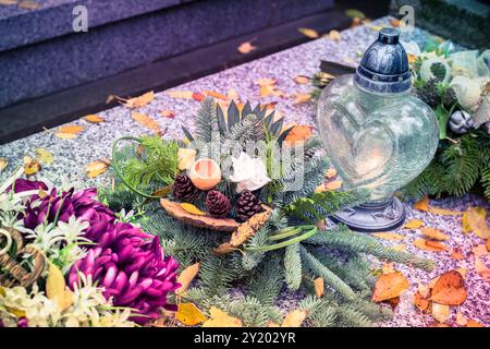 tombe decorate con lanterne, candele accese, fiori colorati di crisantemo, simboli cattolici Foto Stock