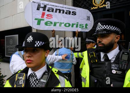 Un unico contrammiratore che regge un cartello che dice “Hamas è un’organizzazione terroristica” rimosso dalla polizia mentre una marcia pro-Palestina è passata b Foto Stock