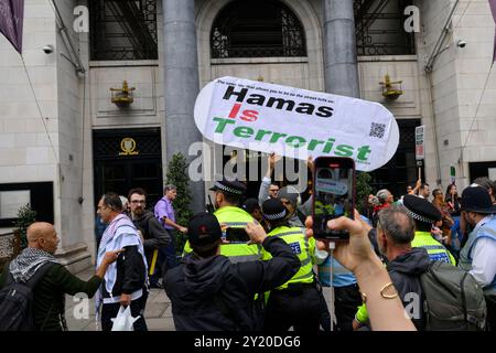 Un unico contrammiratore che regge un cartello che dice “Hamas è un’organizzazione terroristica” rimosso dalla polizia mentre una marcia pro-Palestina è passata b Foto Stock