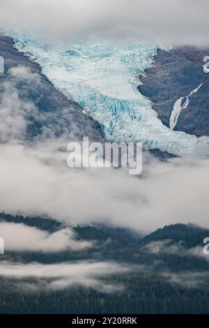 Un ghiacciaio coronato da vette baciate dalle nuvole Foto Stock