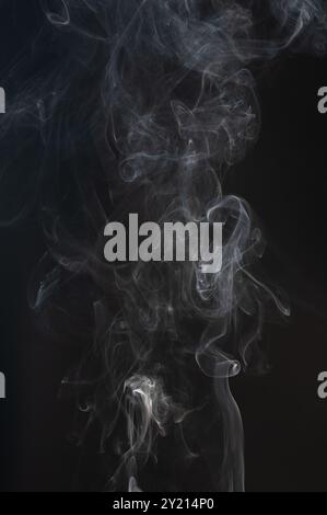 Nuvole di fumo bianche astratte che ruotano isolate su sfondo nero Foto Stock