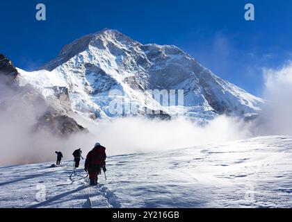 Gruppo di arrampicatori su corda sul ghiacciaio e sul Monte Makalu con nuvole, montagne Nepal Himalaya, valle di Barun Foto Stock