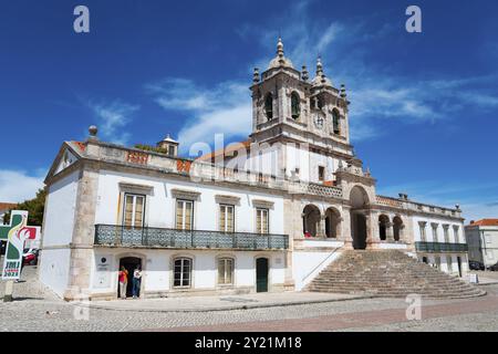 Edificio barocco con torri suggestive, ampi gradini in pietra e facciate luminose sotto un cielo blu, Santuario de Nossa Senhora da Nazare, Santuario Foto Stock