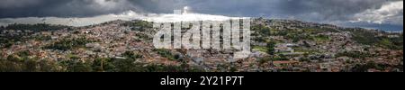 Vista aerea panoramica con sole e cielo nuvoloso scuro della storica città di Diamantina, annidata contro la montagna, Minas Gerais, Brasile, South Amer Foto Stock