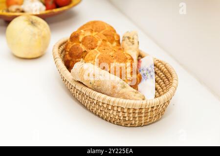 Pani assortiti in un cestino su un tavolo bianco, appena sfornati, prodotti da forno tradizionali, una varietà di pane di frumento e segale in cesto intrecciato, bbra Foto Stock