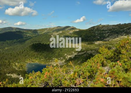 Un pittoresco lago circondato dalla taiga di montagna e un'ombra dalle nuvole sui dolci pendii in una giornata estiva. Rainbow Lake, Ergaki Nature Park, K Foto Stock