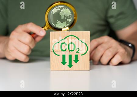 Monta a mano l'icona di riduzione della CO2 sul cubo di legno a blocchi sulla natura per ridurre le emissioni di CO2, l'impronta di carbonio e il credito di carbonio per limitare il riscaldamento globale da clim Foto Stock