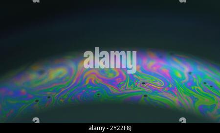 Inchiostro psichedelico. Liquido arcobaleno. Miscela liquida con bolle d'olio colorate sfocate in curva su sfondo nero astratto. Foto Stock