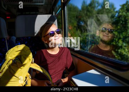 Ragazza seduta in treno, guardando fuori dalla finestra e godendo il viaggio. La famiglia fa un'escursione, usando i mezzi pubblici. Foto Stock