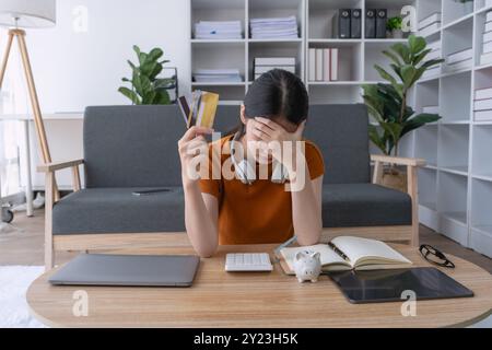 la donna si sente stressata mentre si confronta con il debito di credito, sopraffatta dal peso finanziario e che fatica a trovare una soluzione alla sua situazione difficile Foto Stock