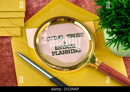 FIDUCIA e PIANIFICAZIONE IMMOBILIARE scritte su un pezzo di carta da una busta attraverso una lente d'ingrandimento Foto Stock