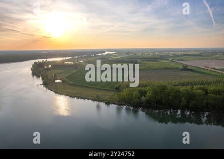 Il tranquillo sentiero di ghiaia si snoda lungo la tranquilla riva di un lago al tramonto, con una luce dorata che si riflette nelle acque calme, creando una scena tranquilla, po R. Foto Stock