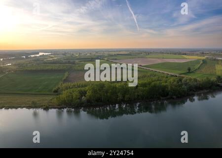 Il tranquillo sentiero di ghiaia si snoda lungo la tranquilla riva di un lago al tramonto, con una luce dorata che si riflette nelle acque calme, creando una scena tranquilla, po R. Foto Stock