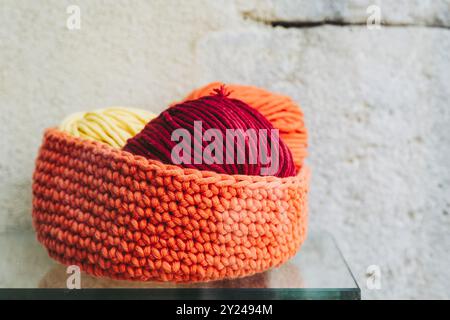 Bellissimo cestino in lana lavorato a mano in arancione con palline di lana Foto Stock