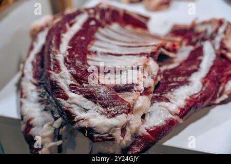 Un grosso pezzo di carne viene tagliato a pezzi più piccoli Foto Stock