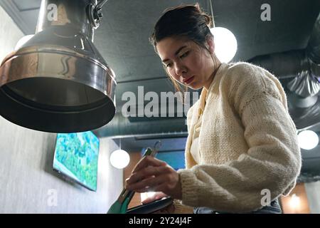 La donna asiatica cucina la carne nella padella sulla stufa nelle regate Foto Stock