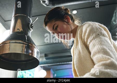 La donna asiatica cucina la carne nella padella sulla stufa nelle regate Foto Stock