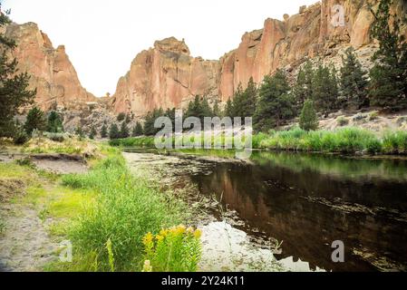 Fiume calmo che riflette le torreggianti scogliere rosse dello Smith Rock State Park. Foto Stock