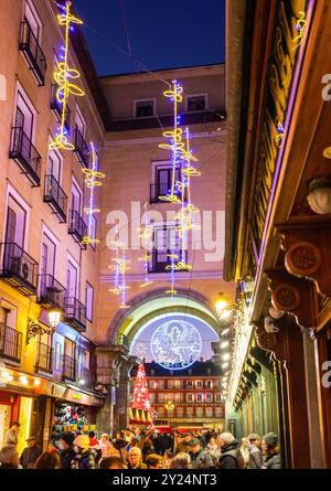 Le decorazioni natalizie illuminano Calle de la Sal con luci al calar della notte. Un passaggio ad arco sullo sfondo conduce a Plaza Mayor. Madrid, Spagna. Foto Stock