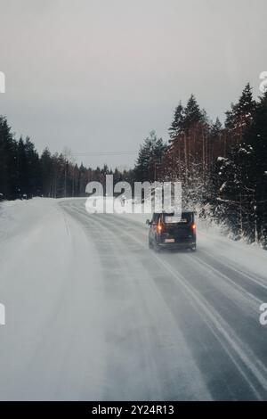 Auto su strada attraverso la foresta nevosa di Lappi a Ranua, Lapponia Foto Stock