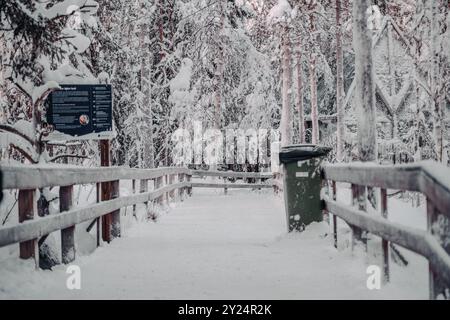 Sentiero con barriere di legno attraverso la foresta innevata di Ranua, Lapponia Foto Stock