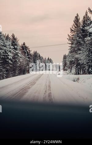 Strada ghiacciata attraverso la foresta lappone all'alba a Rovaniemi, Lapponia in inverno Foto Stock