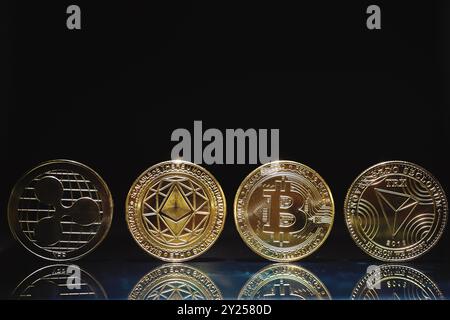 Bitcoin, Ethereum, XRP e TRX monete d'oro su sfondo nero. Concetto finanziario e di investimento. Foto Stock