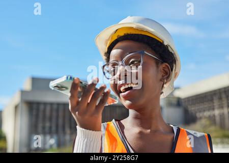 Lavoratrice edile sorridente che utilizza uno smartphone all'aperto Foto Stock