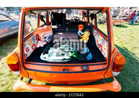 Area di carico posteriore aperta di uno schienale basso volkswagen di tipo 3 arancione con decorazioni retrò e valigia vintage in occasione di una mostra di auto all'aperto Foto Stock