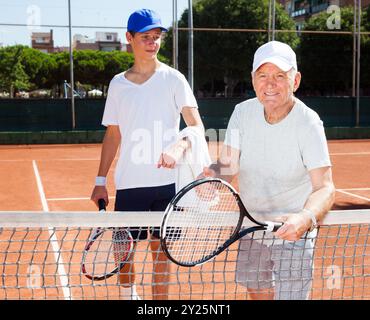 Nonno e nipote in posa sul campo da tennis Foto Stock