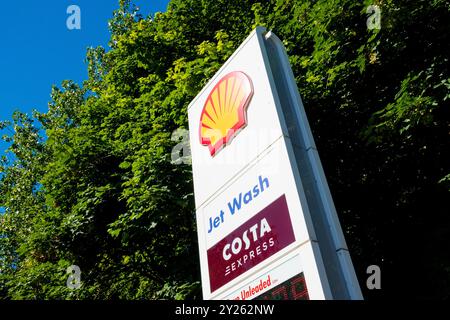 Newcastle Regno Unito: 8 luglio 2024: Cartello di servizio di lavaggio a getto presso una stazione di servizio Shell circondata da vegetazione lussureggiante in una giornata di sole Foto Stock