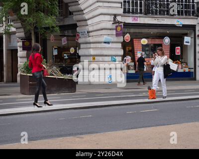 Fotografa influencer che fotografa una modella in Regent Street, indossa abiti da donna con borsa. Foto Stock