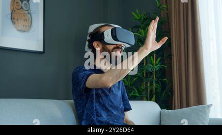 L'uomo che indossa un visore VR esplora l'esperienza di realtà virtuale. Interazione con l'ambiente virtuale Foto Stock