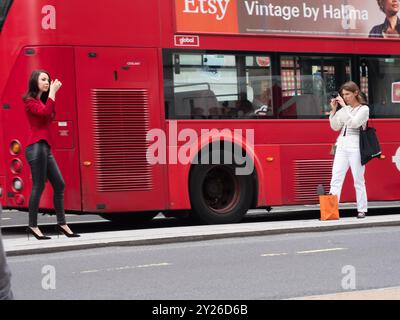 Fotografa influencer che fotografa una modella in Regent Street, indossa abiti da donna con borsa. Foto Stock