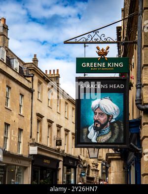 Vista sulla strada di un edificio storico con un cartello da pub per Greene King che mostra Saracens Head nella storica città di Bath, Regno Unito. Foto Stock