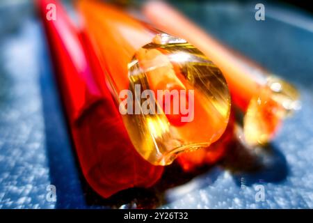 Vista ravvicinata intenzionalmente sfocata di un'asta di vetro colorata con nucleo e rivestimento. immagine macro Foto Stock