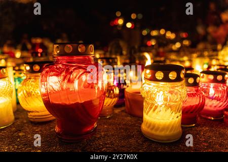 candela a forma di cuore tra le candele scintillanti nella notte al cimitero di tutti i santi, il giorno dei morti o il giorno della memoria Foto Stock