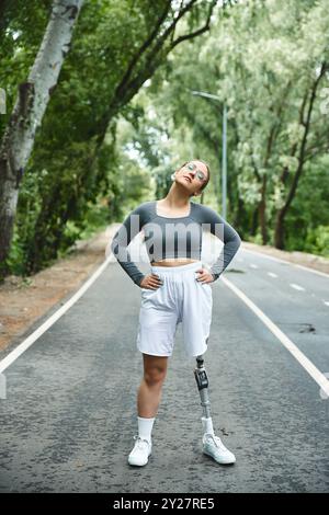 Una giovane donna di abbigliamento sportivo posa con sicurezza all'aperto, mostrando la sua forza e determinazione. Foto Stock