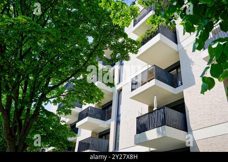 molti piccoli balconi su un nuovo edificio con appartamenti singoli con alberi in primo piano a colonia Foto Stock